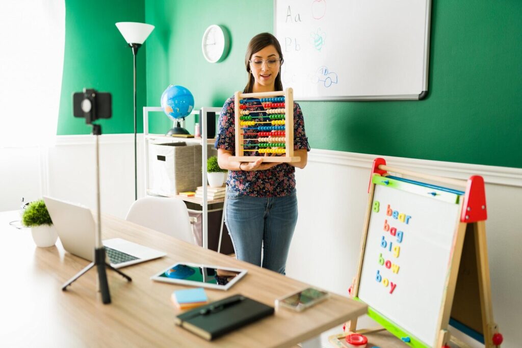 A person holds a colorful abacus in a bright classroom