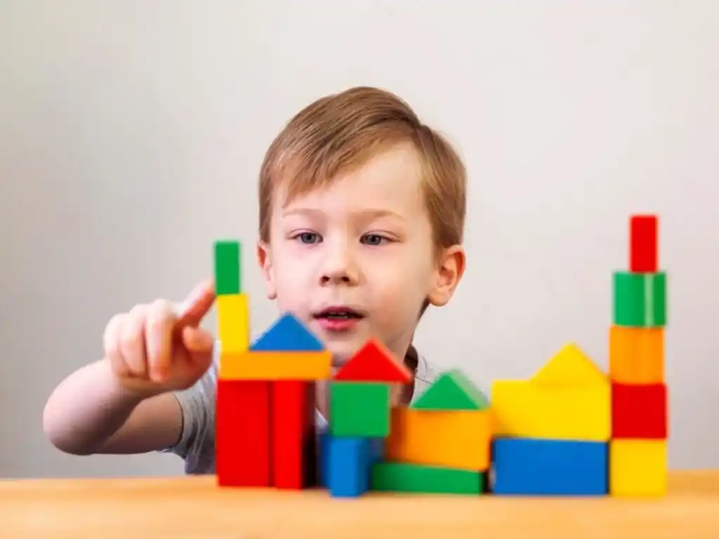A child playing with colorful building blocks, stacking and arranging them on a table, focused on creating structures.