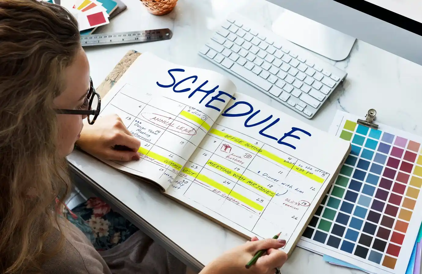 A person writing SCHEDULE, with colorful highlights on various dates.