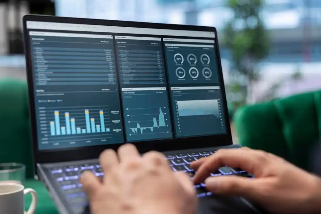 person typing on a laptop displaying data charts