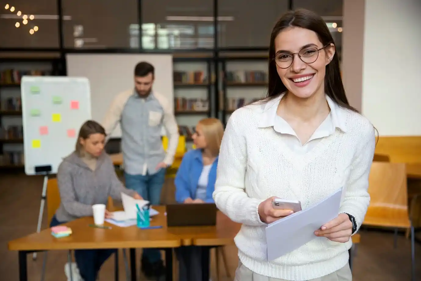group meeting in a bright room with a woman holding a phone