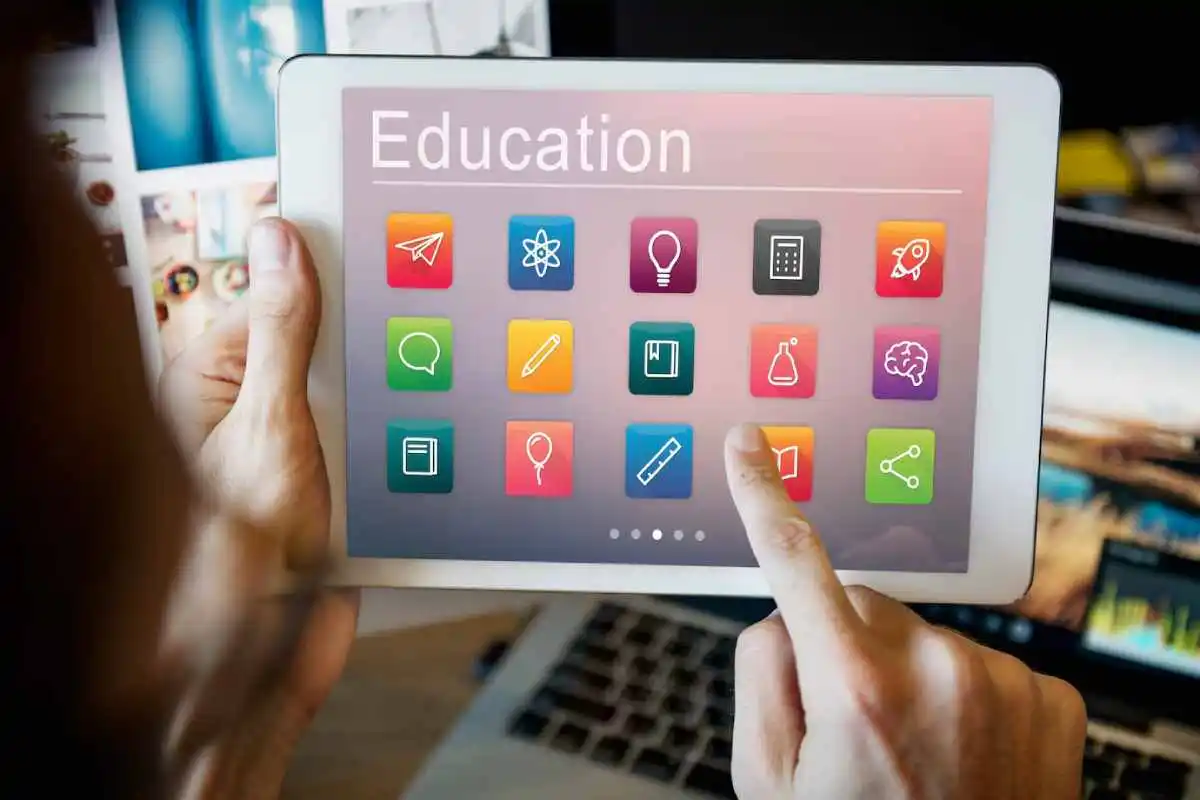person interacting with a tablet displaying colorful educational icons