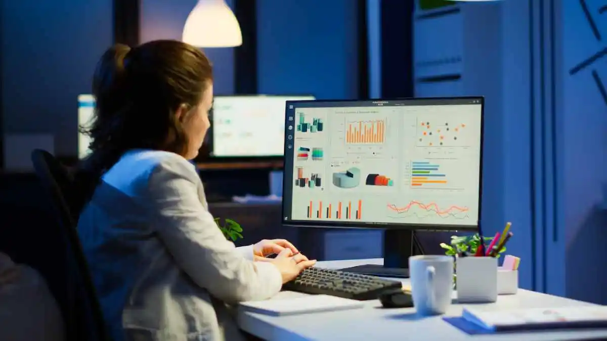 woman working at night in front of computer taking notes 