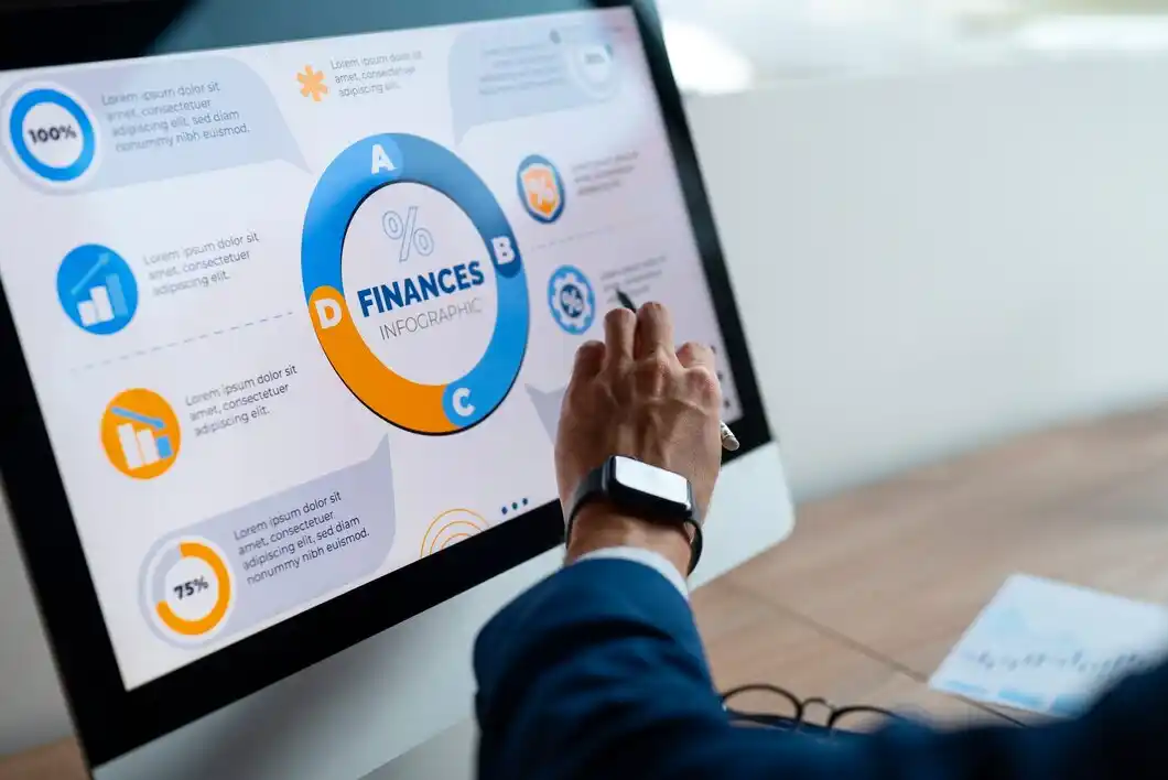 A person interacts with a computer screen displaying a colorful financial infographic, analyzing data points.