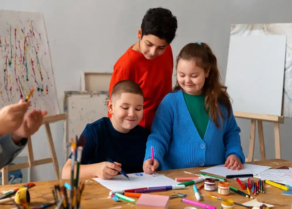 Children engaged in a creative art session, drawing with colorful markers and crayons on a table.