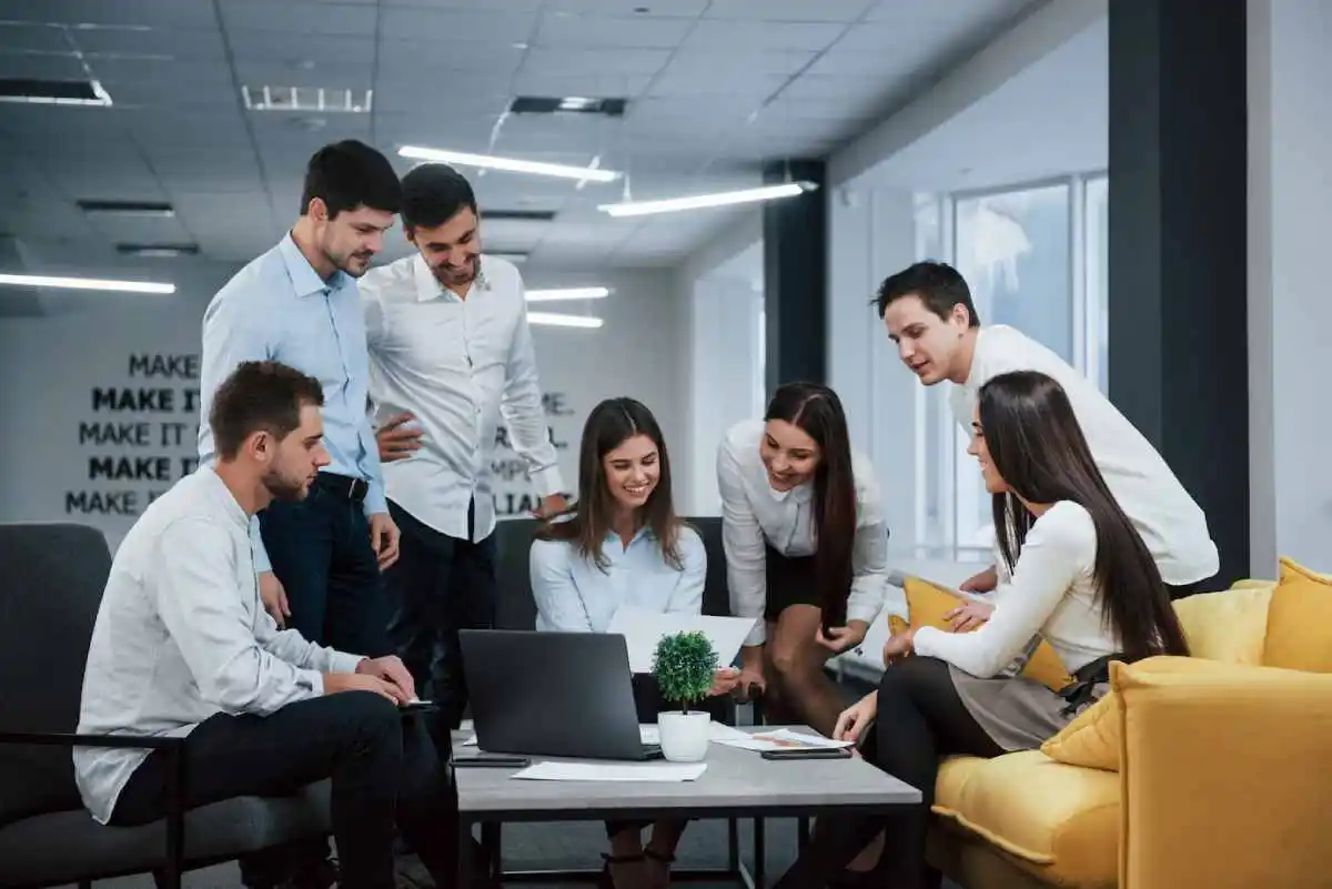 group of professionals collaborates around a laptop in a modern office
