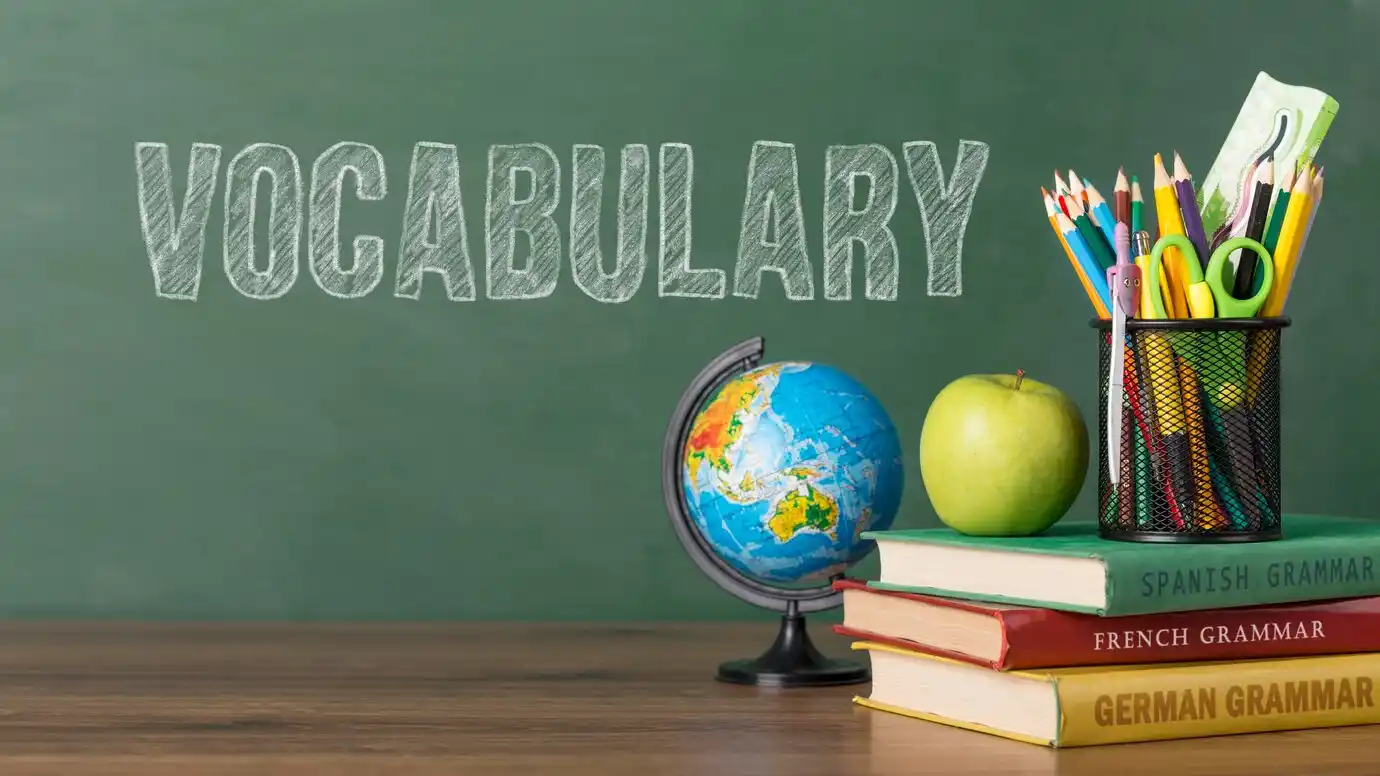 A classroom scene displaying Vocabulary, a globe, and stacked grammar books beside a pencil holder.