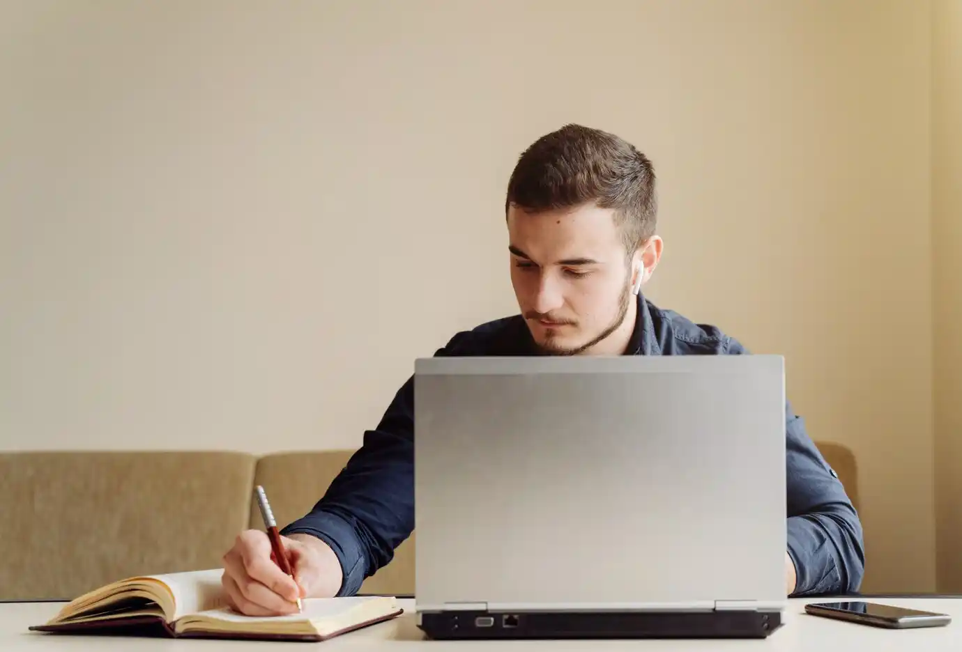 person in a blue shirt works intently on a laptop