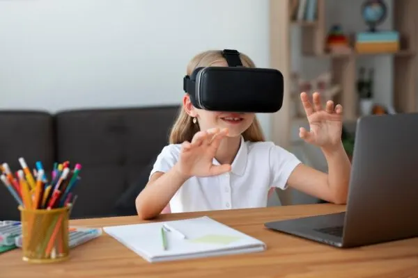 child wearing a virtual reality headset engages with a computer at a desk